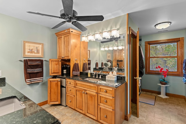 kitchen with ceiling fan, sink, and dark stone counters