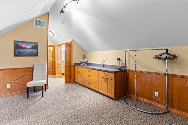 interior space with light carpet, wood walls, and vaulted ceiling