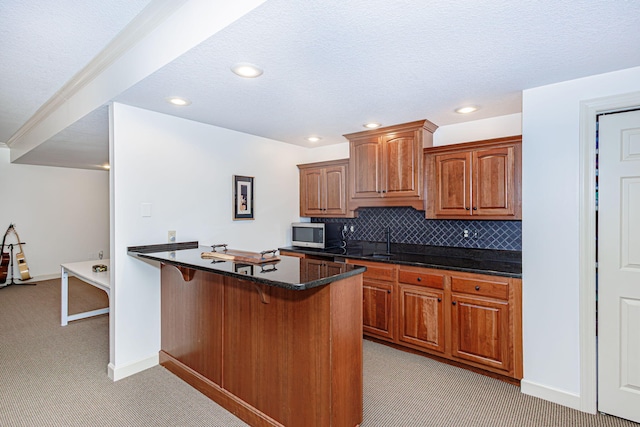 kitchen featuring a breakfast bar, backsplash, light carpet, dark stone counters, and sink