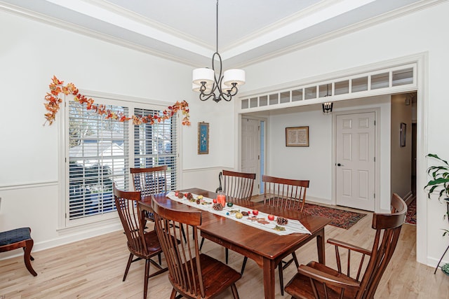 dining room with light wood-type flooring, ornamental molding, and a notable chandelier