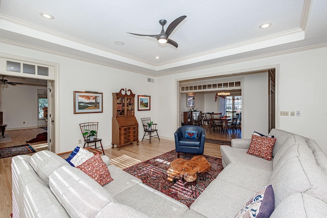 living room with hardwood / wood-style flooring, ceiling fan with notable chandelier, and crown molding