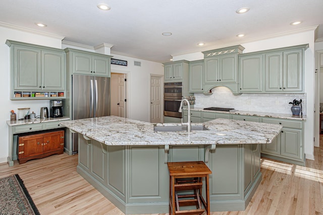 kitchen featuring light wood-type flooring, an island with sink, stainless steel appliances, and sink