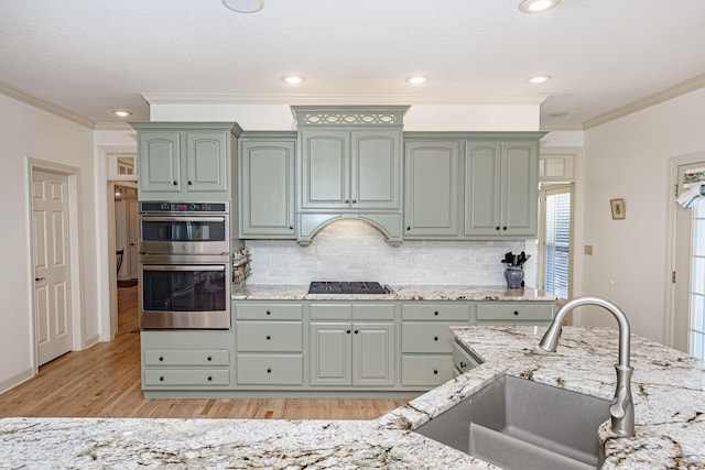 kitchen featuring green cabinets, sink, light hardwood / wood-style flooring, ornamental molding, and stainless steel double oven