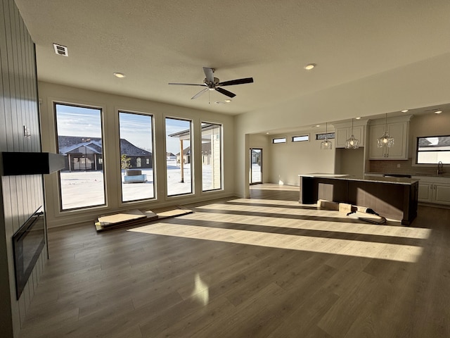 unfurnished living room with ceiling fan with notable chandelier and dark hardwood / wood-style flooring