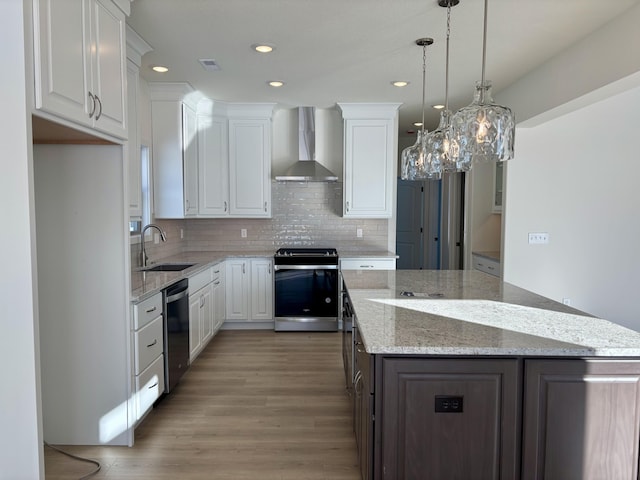 kitchen with white cabinets, wall chimney exhaust hood, sink, and appliances with stainless steel finishes