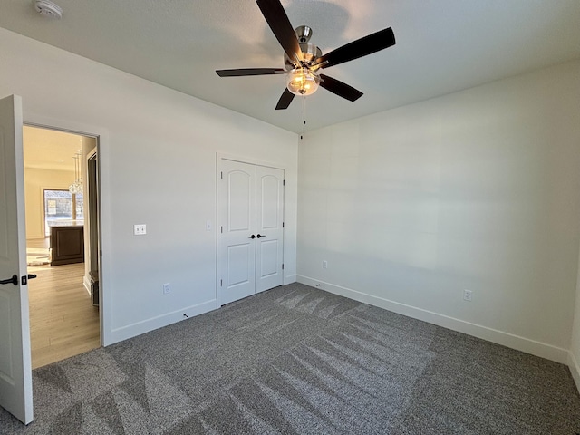 unfurnished bedroom featuring ceiling fan, a closet, and dark carpet