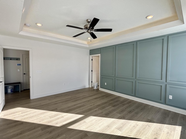 unfurnished bedroom with a raised ceiling, ceiling fan, and dark hardwood / wood-style floors