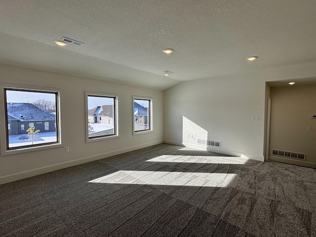 carpeted spare room with a textured ceiling and vaulted ceiling