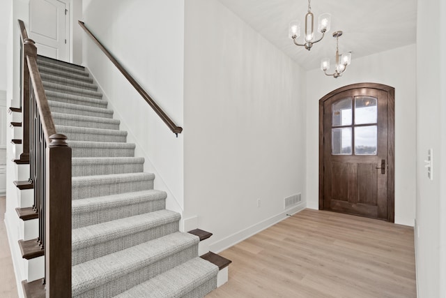 6504 Walsby Dr, Columbia, MO 65201 - foyer with stairs, light wood-type flooring, arched walkways, an inviting chandelier, and visible vents