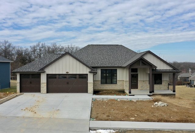 view of front of property featuring board and batten siding, stone siding, a garage, and concrete driveway