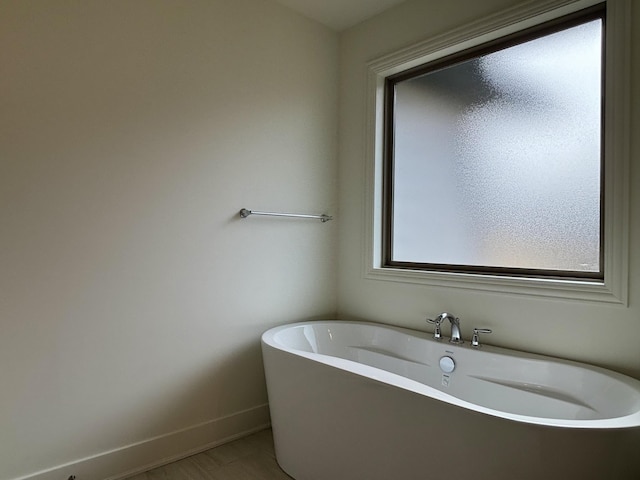 bathroom featuring a soaking tub and baseboards