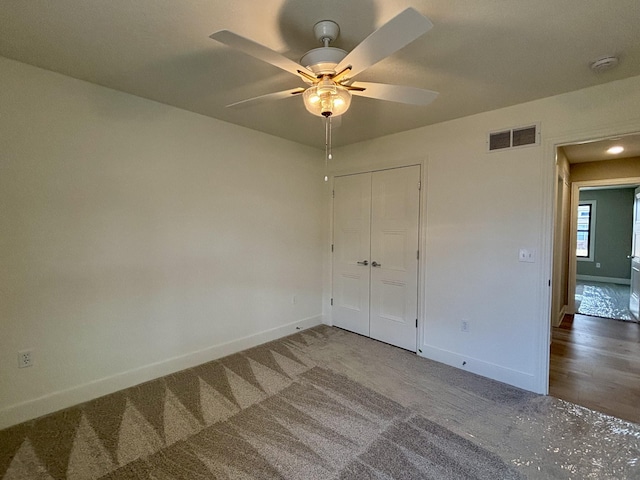 unfurnished bedroom with ceiling fan, visible vents, baseboards, a closet, and dark colored carpet