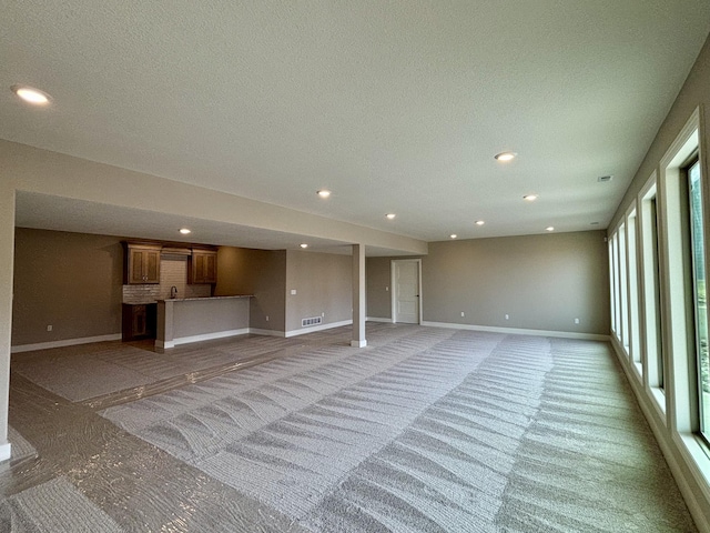 unfurnished living room featuring a textured ceiling, recessed lighting, visible vents, and baseboards