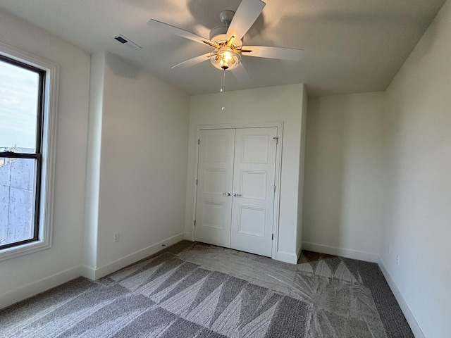 unfurnished bedroom featuring visible vents, baseboards, ceiling fan, carpet, and a closet