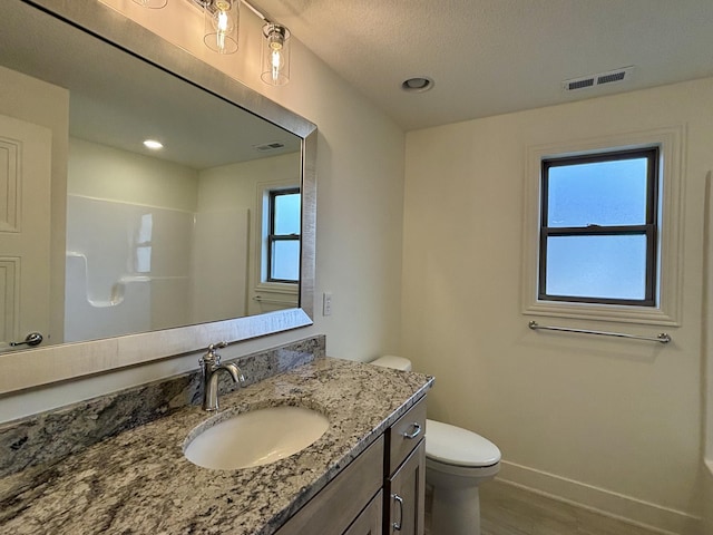 bathroom with baseboards, visible vents, a shower, toilet, and vanity