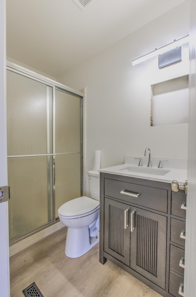 bathroom featuring hardwood / wood-style floors, vanity, toilet, and a shower with door