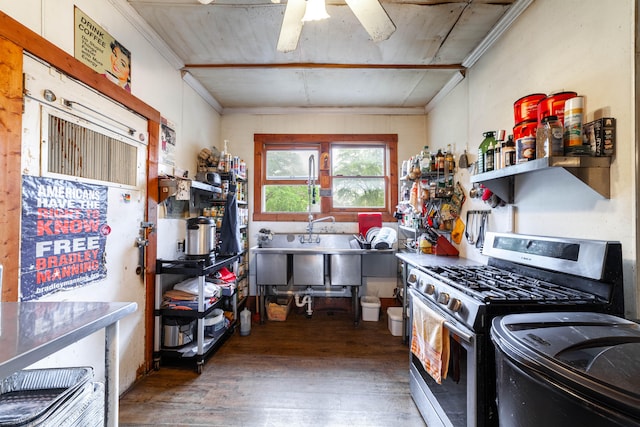 kitchen featuring dark wood-type flooring, stainless steel gas range oven, ceiling fan, and crown molding