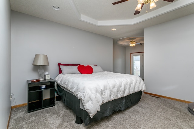 carpeted bedroom with a tray ceiling, a textured ceiling, and ceiling fan