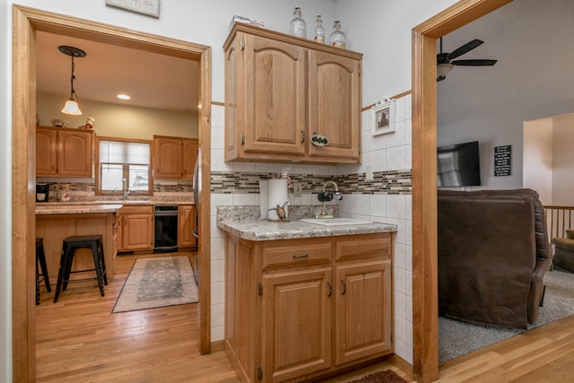 kitchen featuring sink, tasteful backsplash, ceiling fan, decorative light fixtures, and light hardwood / wood-style flooring