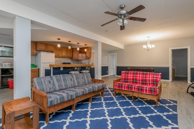 living room with ceiling fan with notable chandelier and light wood-type flooring