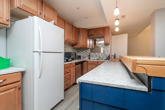 kitchen with pendant lighting, backsplash, white refrigerator, light wood-type flooring, and dishwasher