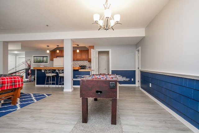 rec room with light hardwood / wood-style floors and a chandelier