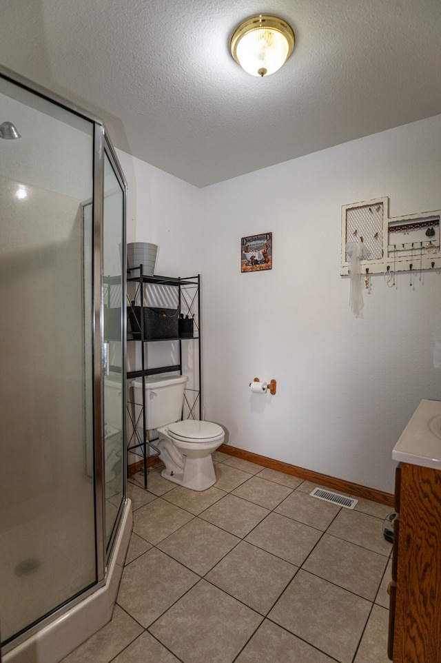 bathroom with tile patterned flooring, vanity, toilet, and a shower with shower door