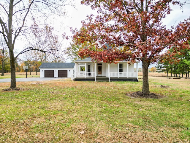 view of front facade with a front lawn, a garage, an outbuilding, and a porch