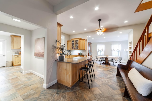 kitchen with ceiling fan, decorative light fixtures, kitchen peninsula, and a breakfast bar area