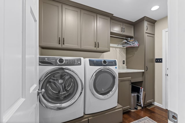 clothes washing area featuring dark wood-type flooring, washing machine and dryer, and cabinets