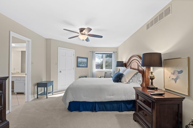 carpeted bedroom with ensuite bathroom and ceiling fan