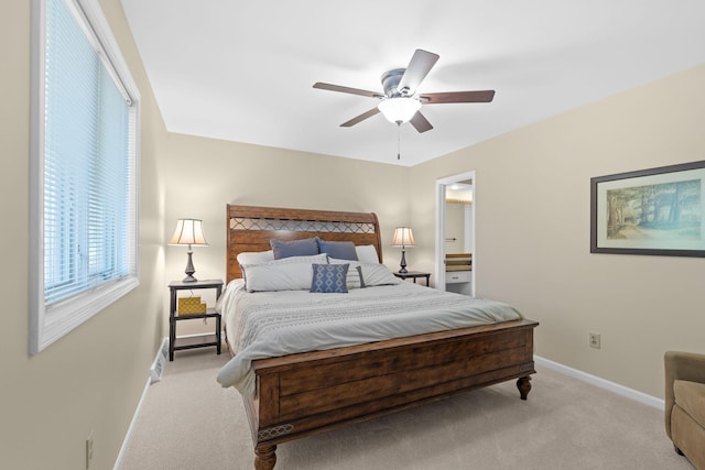 bedroom featuring light colored carpet, ceiling fan, and ensuite bath