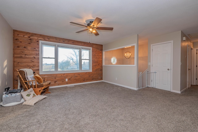 unfurnished room featuring carpet, wooden walls, and ceiling fan