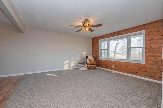 unfurnished room with hardwood / wood-style flooring, wooden walls, and ceiling fan