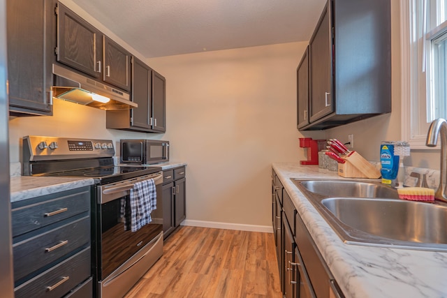 kitchen with appliances with stainless steel finishes, sink, dark brown cabinets, and light hardwood / wood-style floors