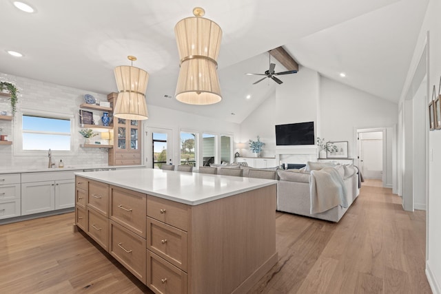 kitchen featuring hanging light fixtures, sink, a kitchen island, white cabinetry, and light wood-type flooring