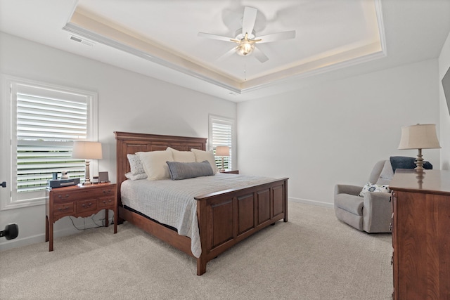 bedroom featuring light colored carpet, ceiling fan, and a tray ceiling