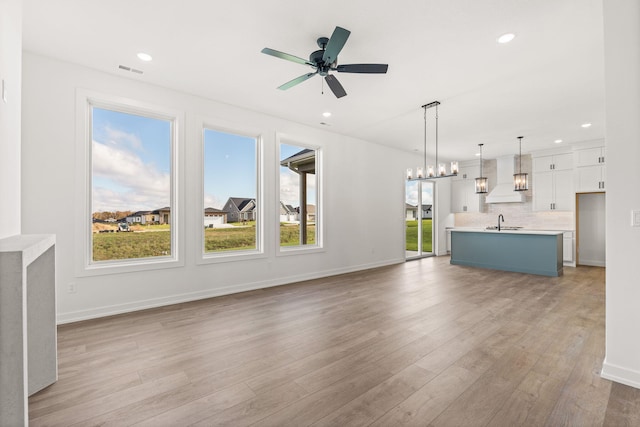 unfurnished living room featuring light hardwood / wood-style floors, ceiling fan, and sink