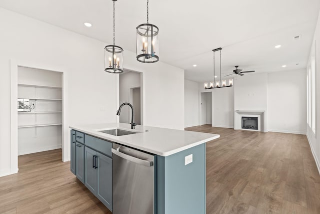 kitchen with dishwasher, hanging light fixtures, sink, an island with sink, and light wood-type flooring