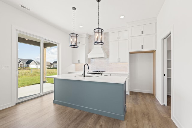 kitchen featuring hardwood / wood-style flooring, white cabinetry, sink, and a kitchen island with sink