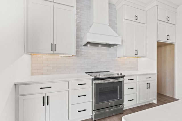kitchen featuring premium range hood, stainless steel range with electric stovetop, white cabinetry, backsplash, and hardwood / wood-style floors