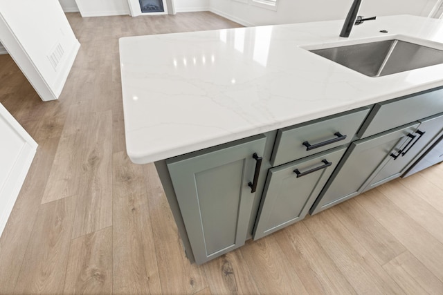 kitchen featuring light hardwood / wood-style floors, sink, and light stone counters