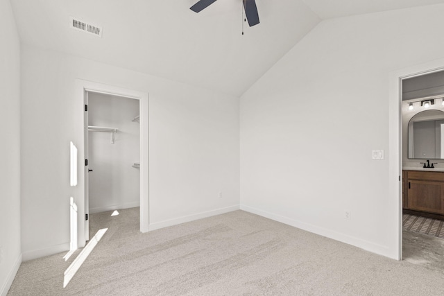 unfurnished bedroom featuring light colored carpet, lofted ceiling, ceiling fan, a closet, and a spacious closet