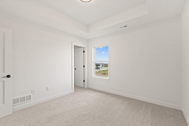 carpeted spare room with a tray ceiling