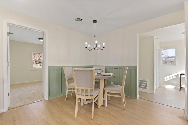 dining space with light wood-type flooring and a notable chandelier