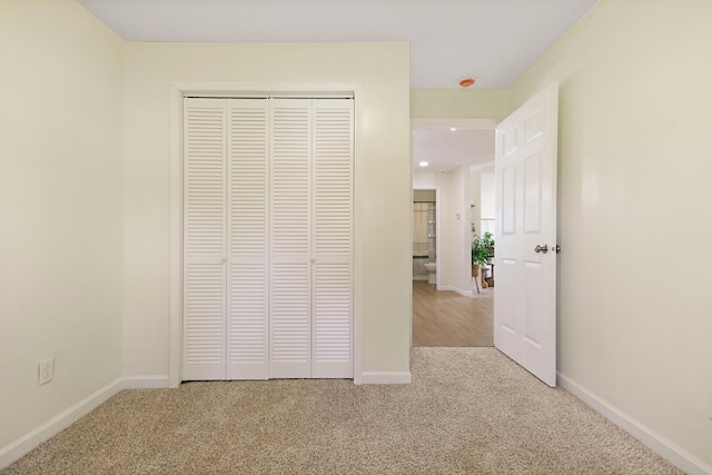 unfurnished bedroom with light carpet and a closet