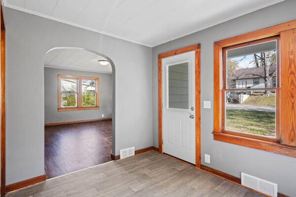 entrance foyer with hardwood / wood-style floors, a healthy amount of sunlight, and ornamental molding