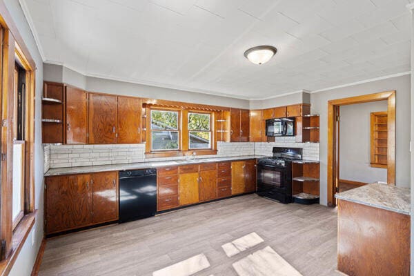 kitchen featuring ornamental molding, light hardwood / wood-style flooring, black appliances, and backsplash