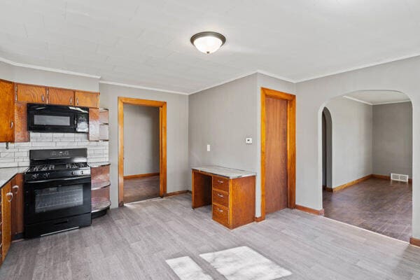 kitchen featuring light wood-type flooring, black appliances, and crown molding