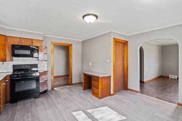 201 N Evans St, Armstrong, MO 65230 - kitchen featuring black appliances, brown cabinets, arched walkways, light wood-type flooring, and light countertops